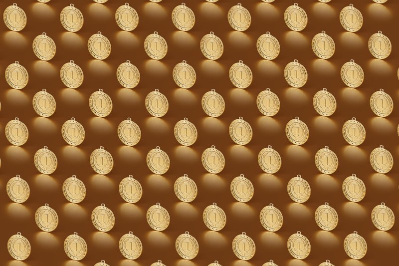 Multiple gold medals arranged in a repeating pattern on a brown backdrop.