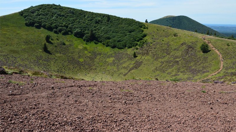 Sweeping view of lush green hills and a volcanic crater under a clear sky.