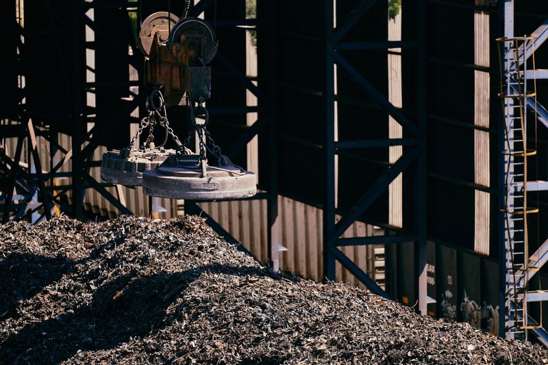 Heavy-duty magnet crane operating in an industrial scrap metal yard.