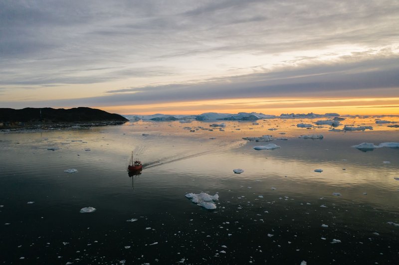 A serene scene of a boat navigating through icebergs under a vibrant Arctic sunset.