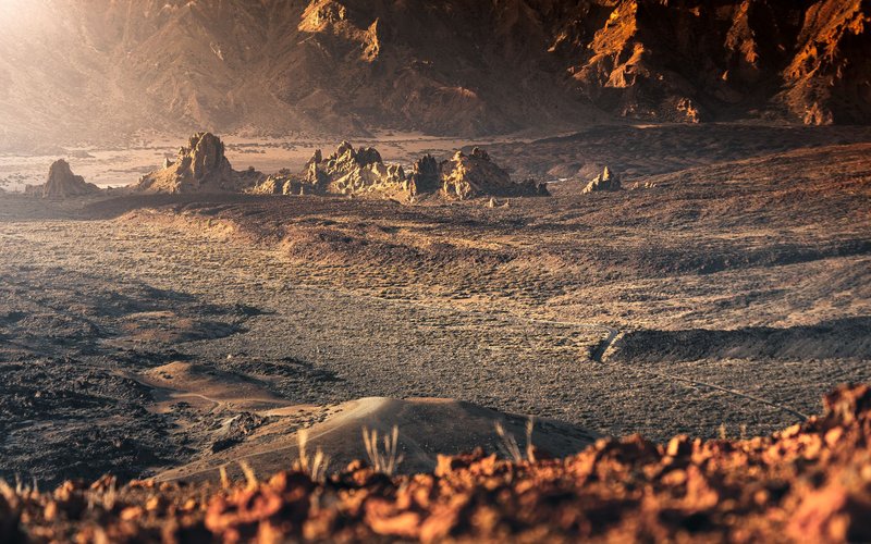 Breathtaking view of Mars-like volcanic terrain under warm sunrise light in Tenerife's national park.