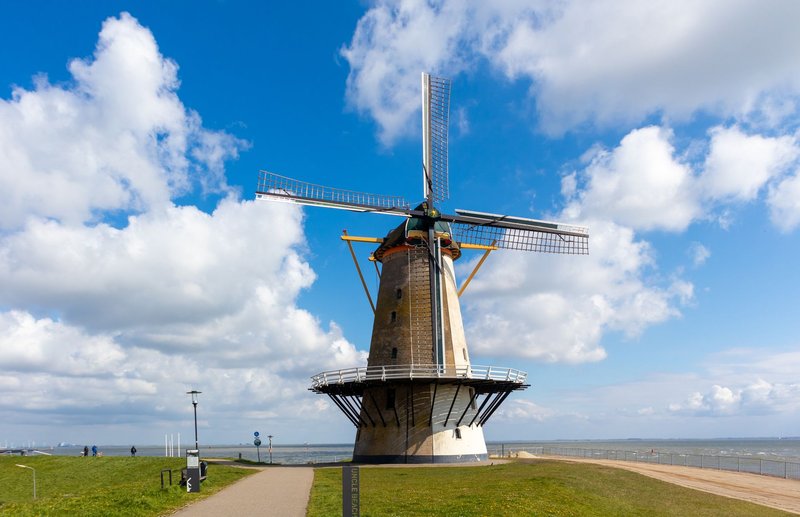 Classic windmill on a sunny day in Vlissingen, Netherlands, near the sea with blue skies.