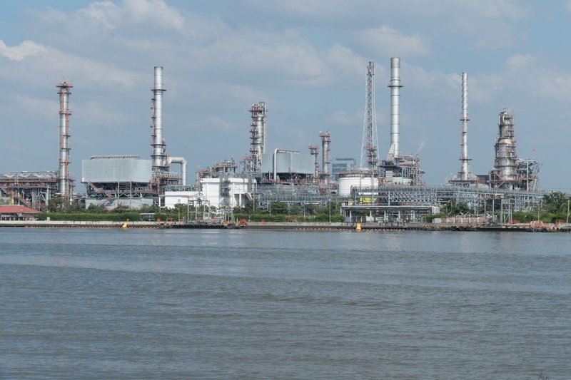A large oil refinery complex next to the water with cloudy skies.
