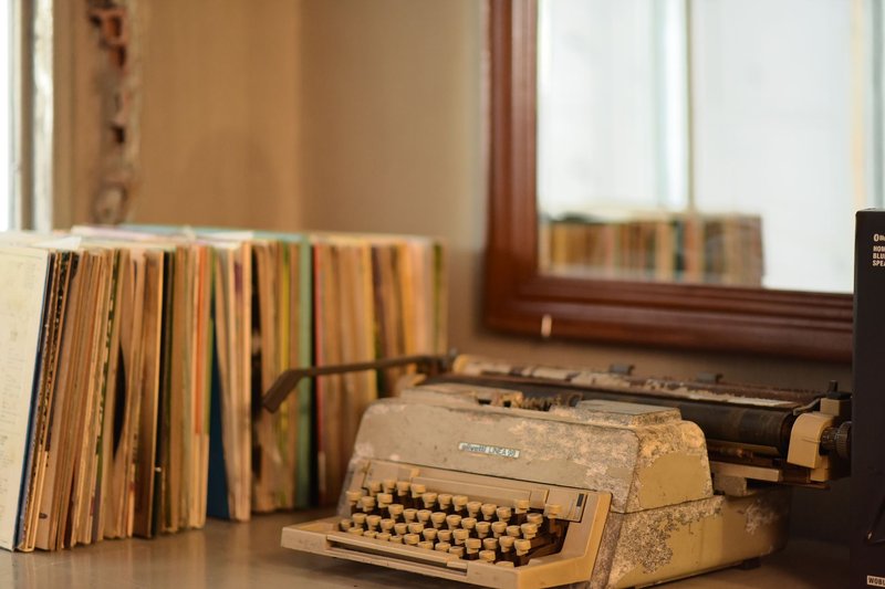 A rustic typewriter beside stacked books reflects nostalgic charm in a vintage setting.