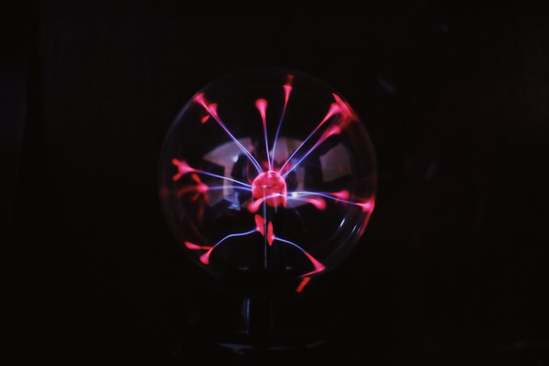 Crystal glass plasma ball with glowing electric lights inside placed in dark room