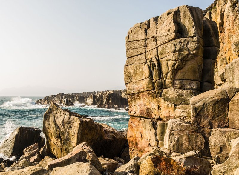A stunning view of coastal cliffs and robust rock formations with waves crashing against them.