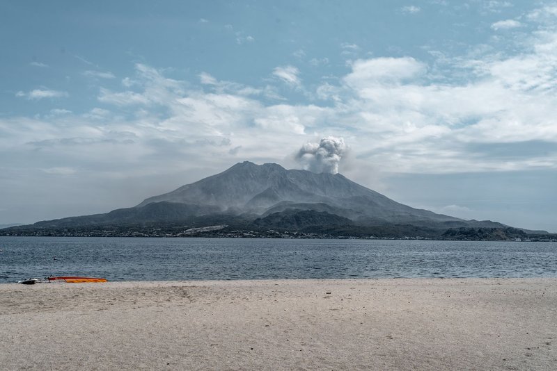 Dramatic view of Sakurajima volcano erupting over a tranquil bay in Kagoshima, Japan.