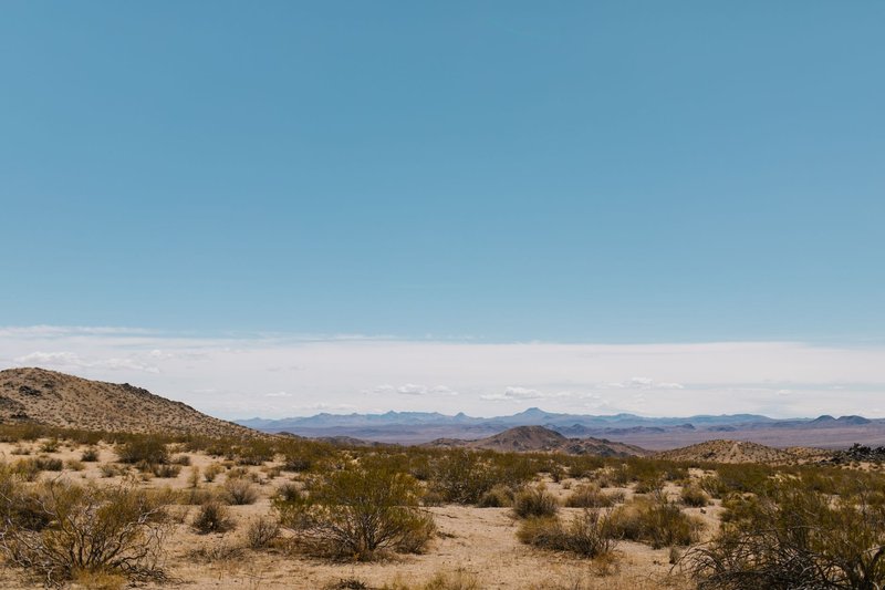 Explore the vast desert landscape under a clear blue sky with distant mountains.