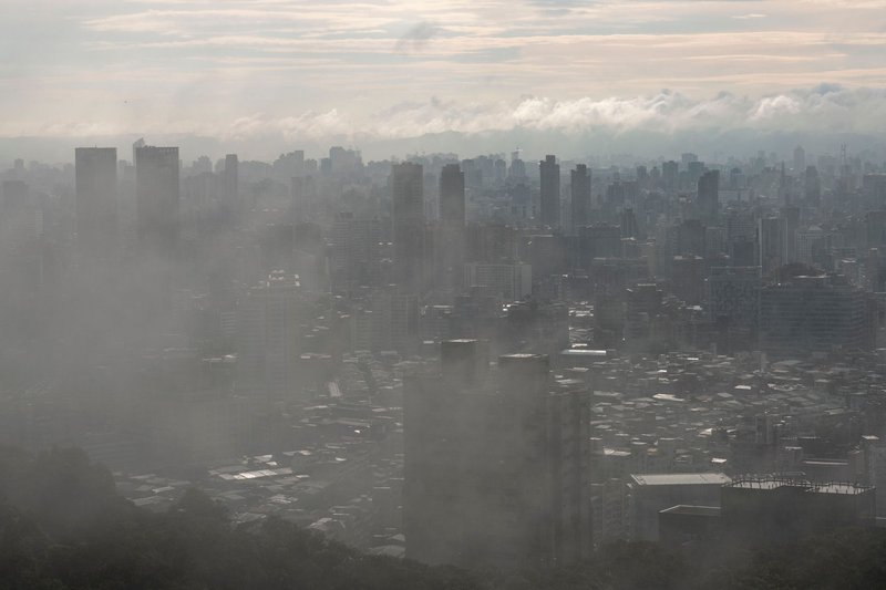 Dramatic view of Taipei's skyline shrouded in fog and atmospheric haze, creating a moody urban scene.