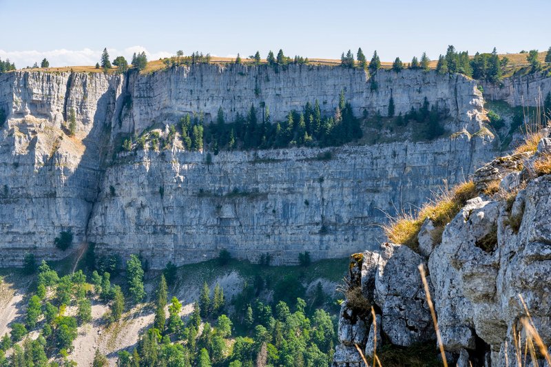 Stunning view of Creux du Van's limestone cliffs in Switzerland displaying natural grandeur.