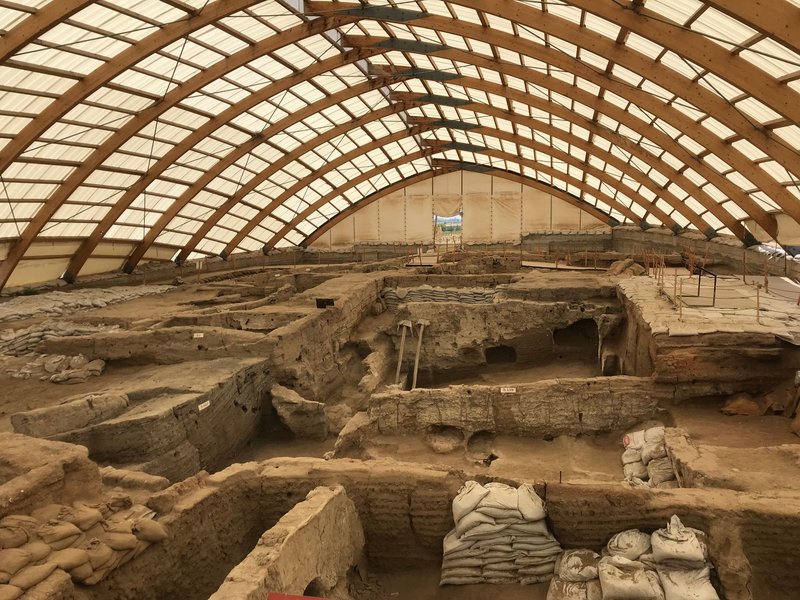 A large indoor archaeological dig showcasing ancient ruins under a protective dome structure.
