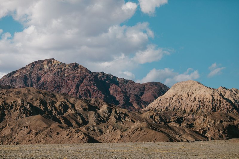 Majestic rocky mountain landscape with clear blue sky and scattered clouds.