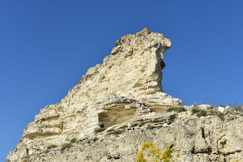 A striking limestone rock formation set against a bright blue sky, showcasing natural erosion patterns.