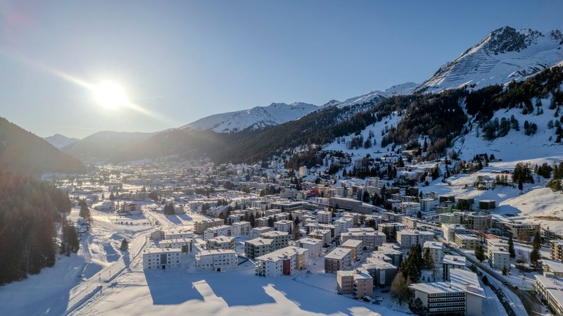 Aerial photo of snowy Davos with sunlit mountains, winter scenery.