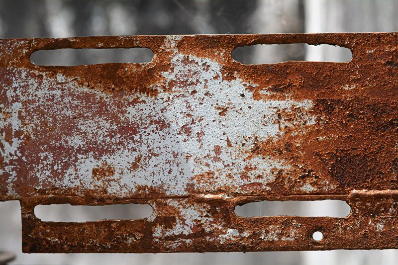 Close-up of a rusty and corroded metal plate with a textured surface.