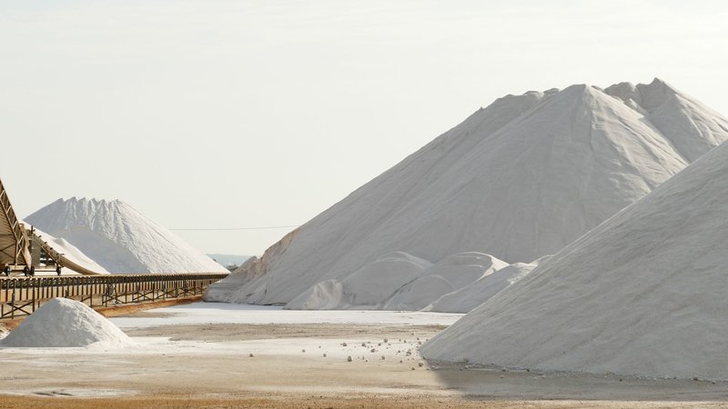 Expansive view of salt mountains and conveyor belt in a salt mine, showcasing industrial beauty.
