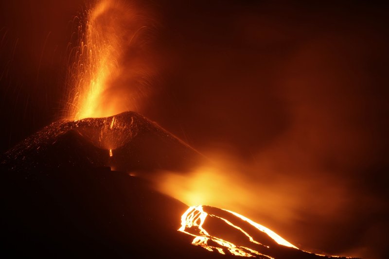 A powerful volcanic eruption at night with flowing lava and sparks creating a dramatic scene.