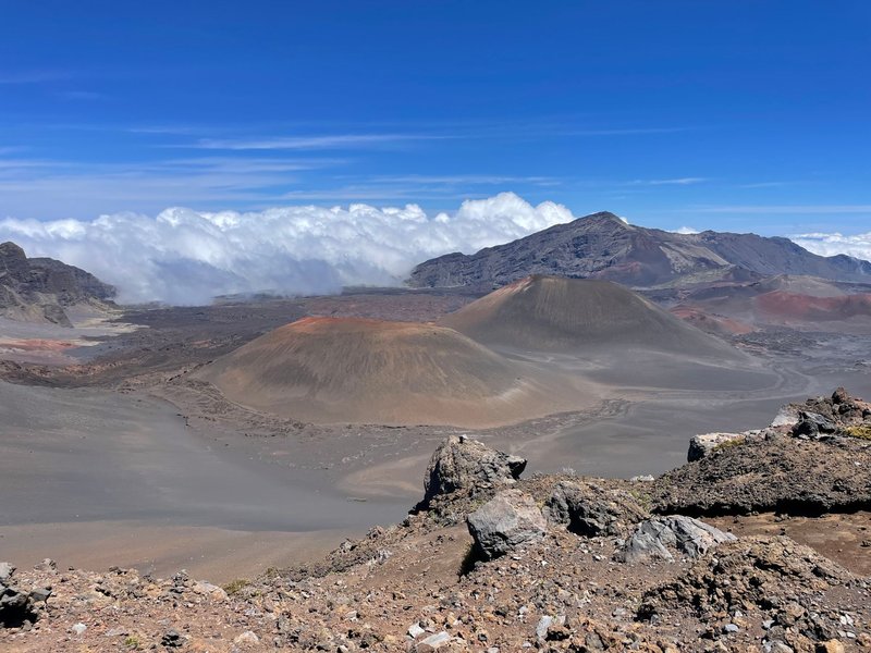 View of Haleakalā Crater with scattered clouds and vibrant terrain in Maui's volcanic landscape.