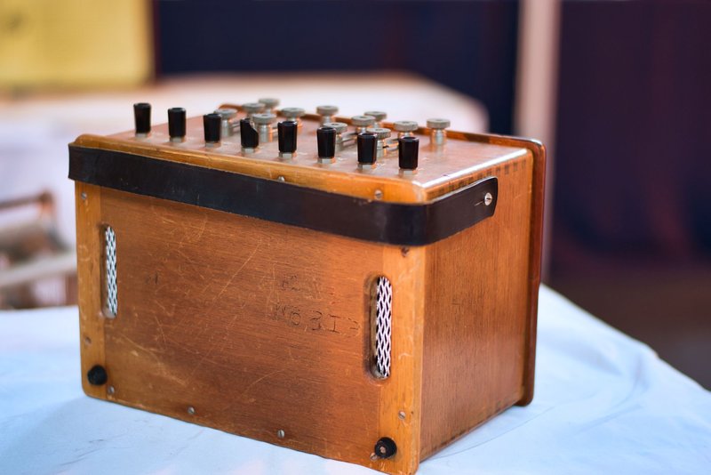 Close-up of a vintage wooden equipment box featuring multiple dials and knobs indoors.