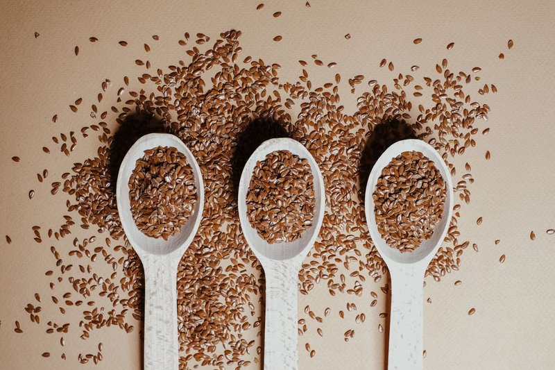 Flat lay of organic flaxseeds in wooden spoons showcasing natural nutrition and texture.
