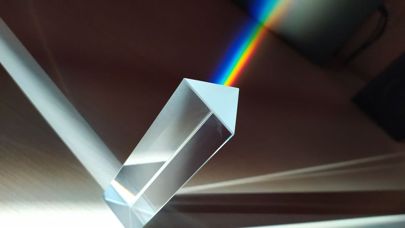A glass prism creates a vivid rainbow reflection, capturing abstract geometric beauty.