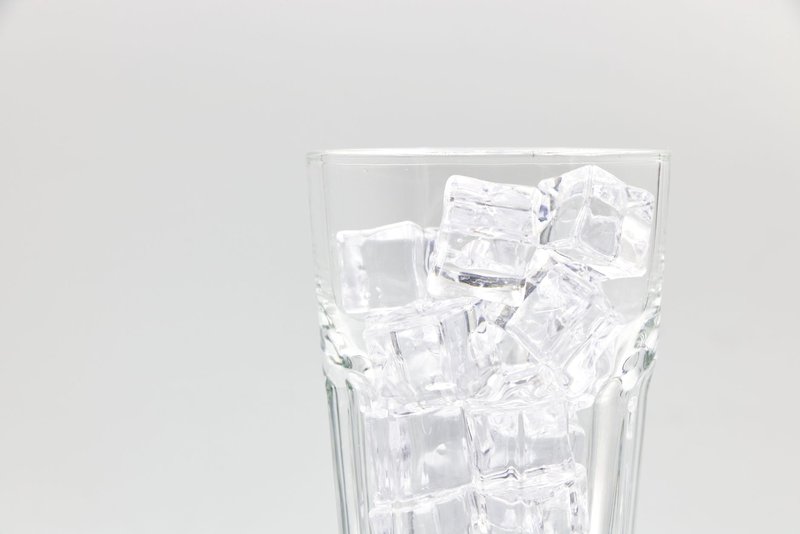 Close-up of a glass filled with ice cubes on a white background.