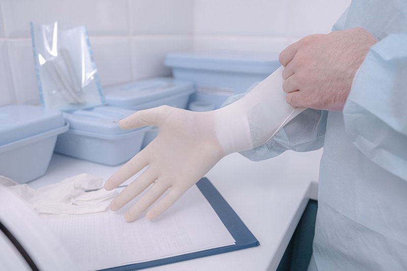 A medical practitioner wearing latex gloves in a clinical setting ensures cleanliness.