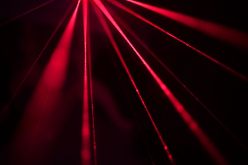 Dynamic red laser beams create a striking abstract pattern in a dark studio setting.