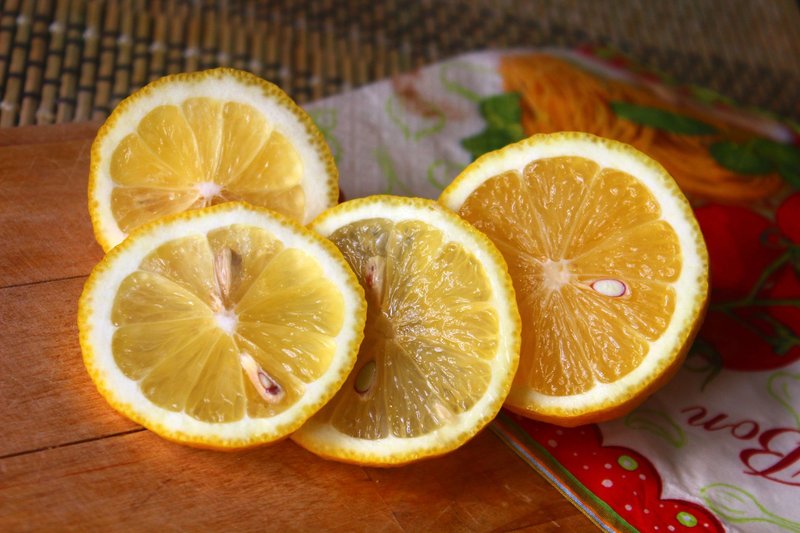 Close-up of juicy lemon slices on a wooden board, showcasing their vibrant texture and freshness.