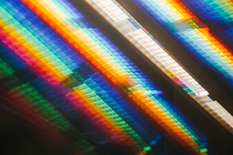 Colorful abstract image featuring a spectrum of rainbow light on a reflective surface.