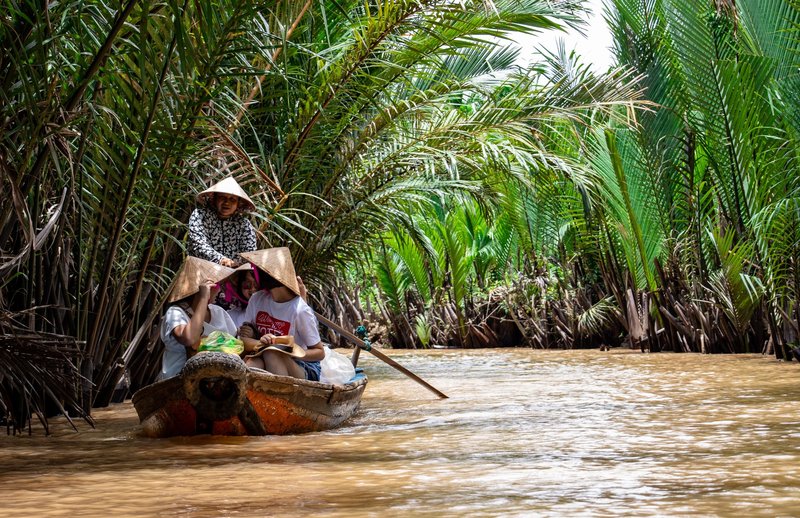 Explore the vibrant scenery on a traditional boat ride through the Mekong Delta's palm-lined waterways.