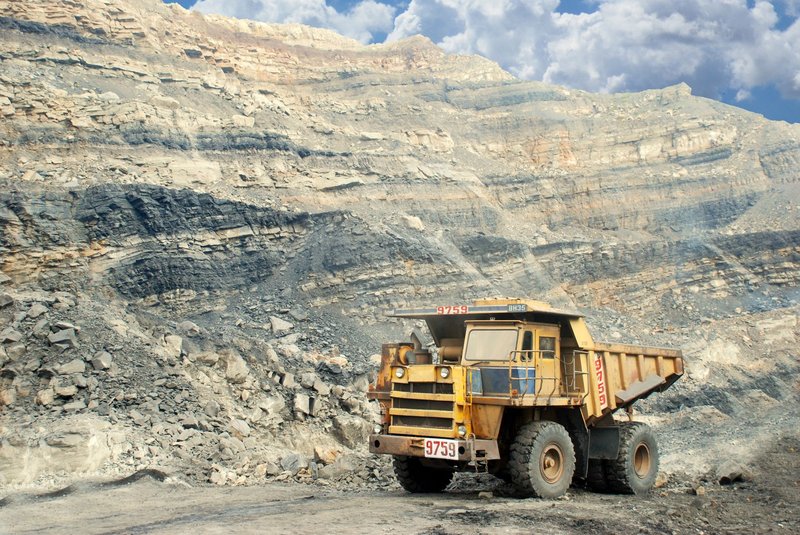 A large yellow mining truck in a rocky quarry under a clear sky.