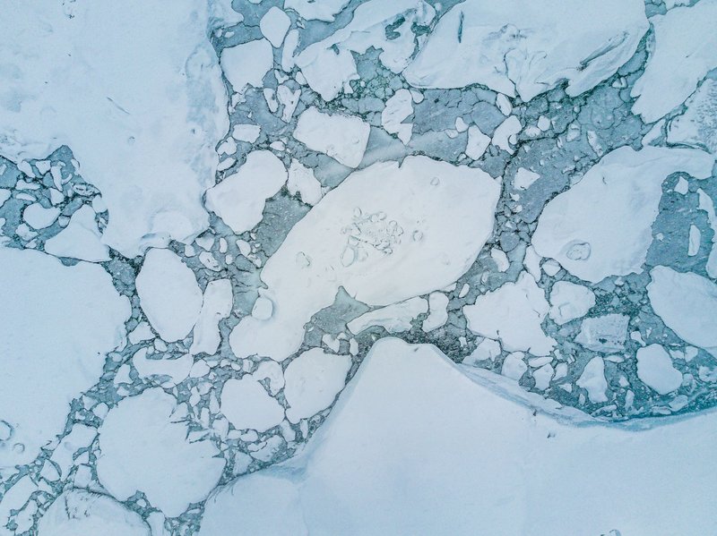 Stunning aerial shot of icy arctic landscape showcasing floating ice and calm winter sea.