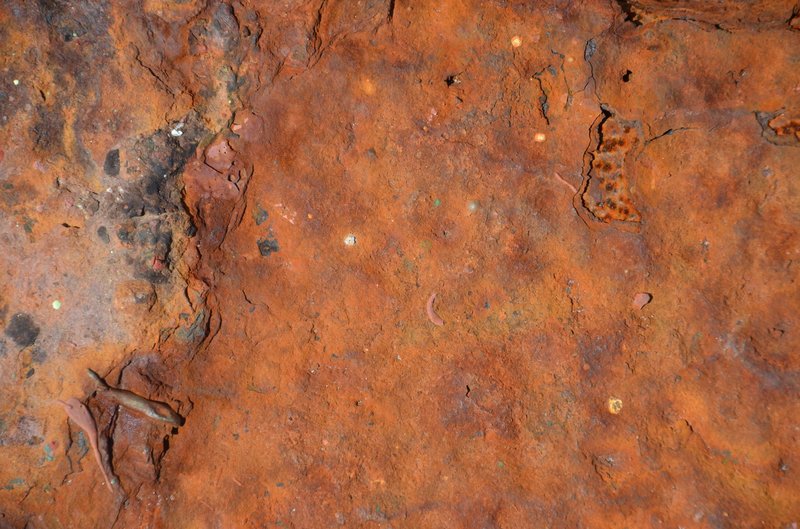 Close-up of a textured rusty metal surface showing corrosion and damage.
