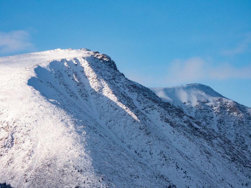 A stunning view of a snow-covered mountain peak under a clear blue sky.