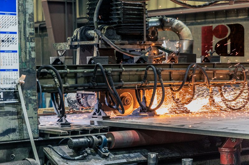 Detailed view of industrial machinery cutting metal, showcasing sparks and heat.