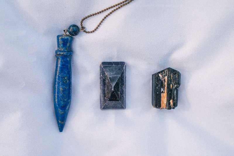 Close-up of three healing crystals laid out in a still life arrangement on white fabric.